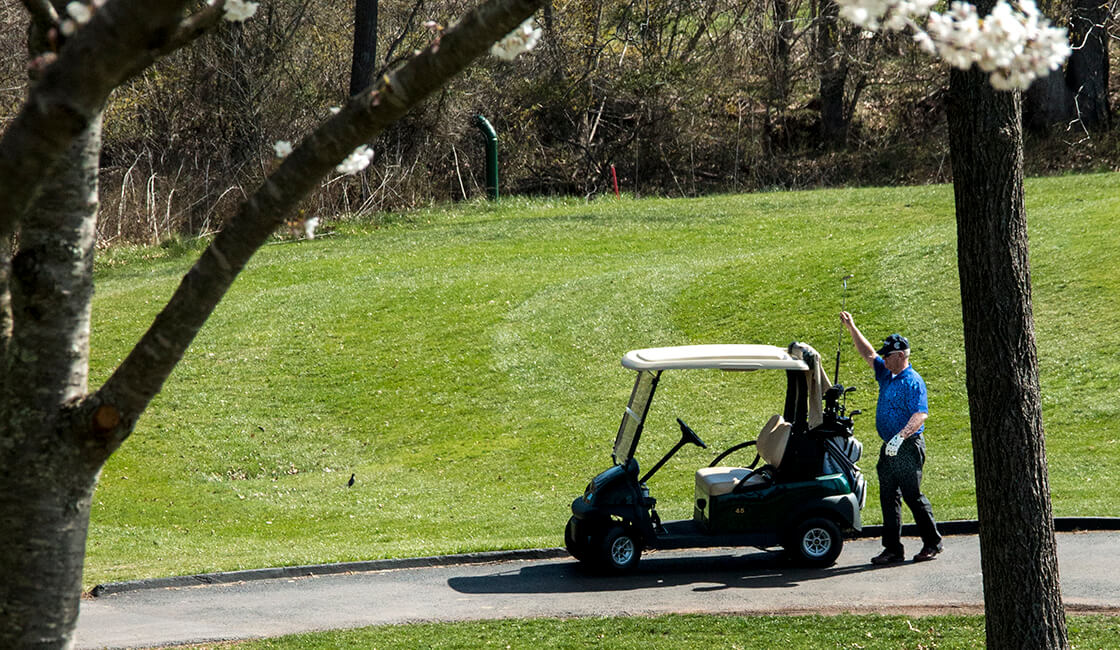 golfer selecting club from bag on golf cart